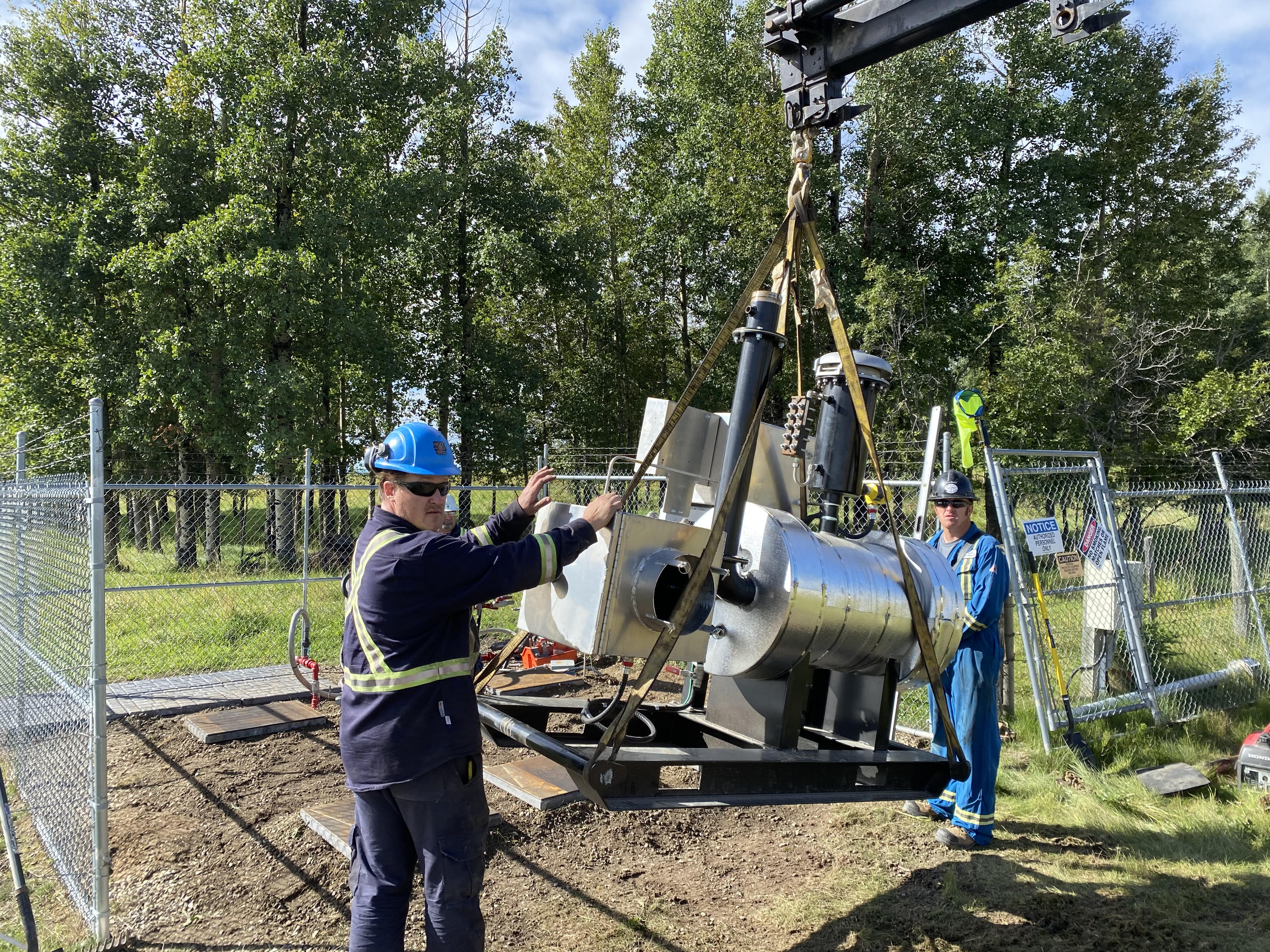 Rocky Gas Co-op workers hoisting equipment components on site.